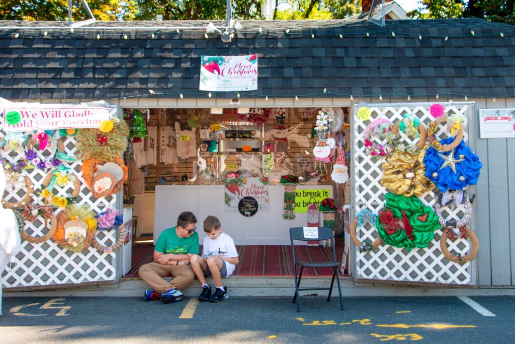 Two boys sitting in front of a vendors shed during the Big E